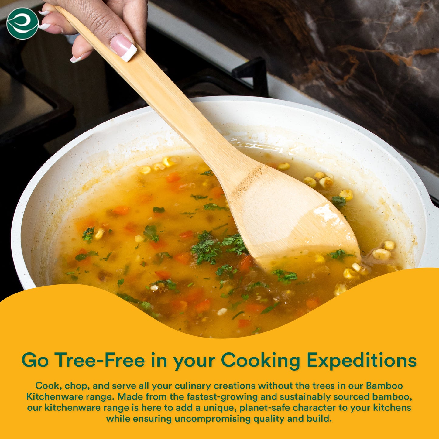Hand stirring soup in a pan using a bamboo spatula, showcasing eco-friendly, tree-free kitchen utensils in use.
